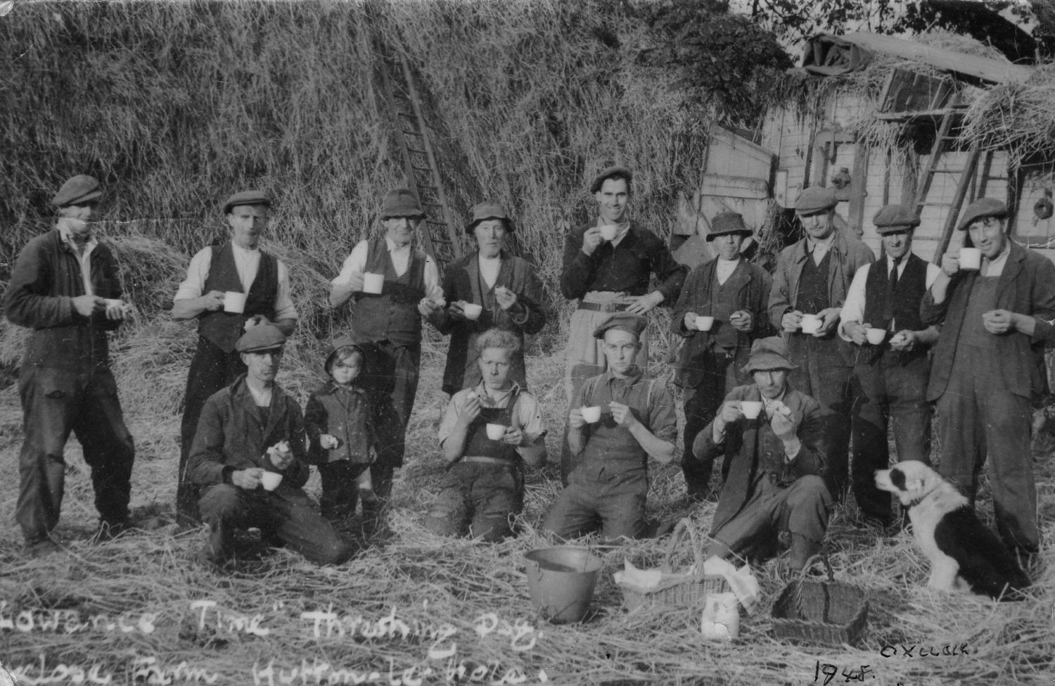 People and children standing and kneeling in front of haystack