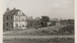 Part demolished house surrounded by grass.