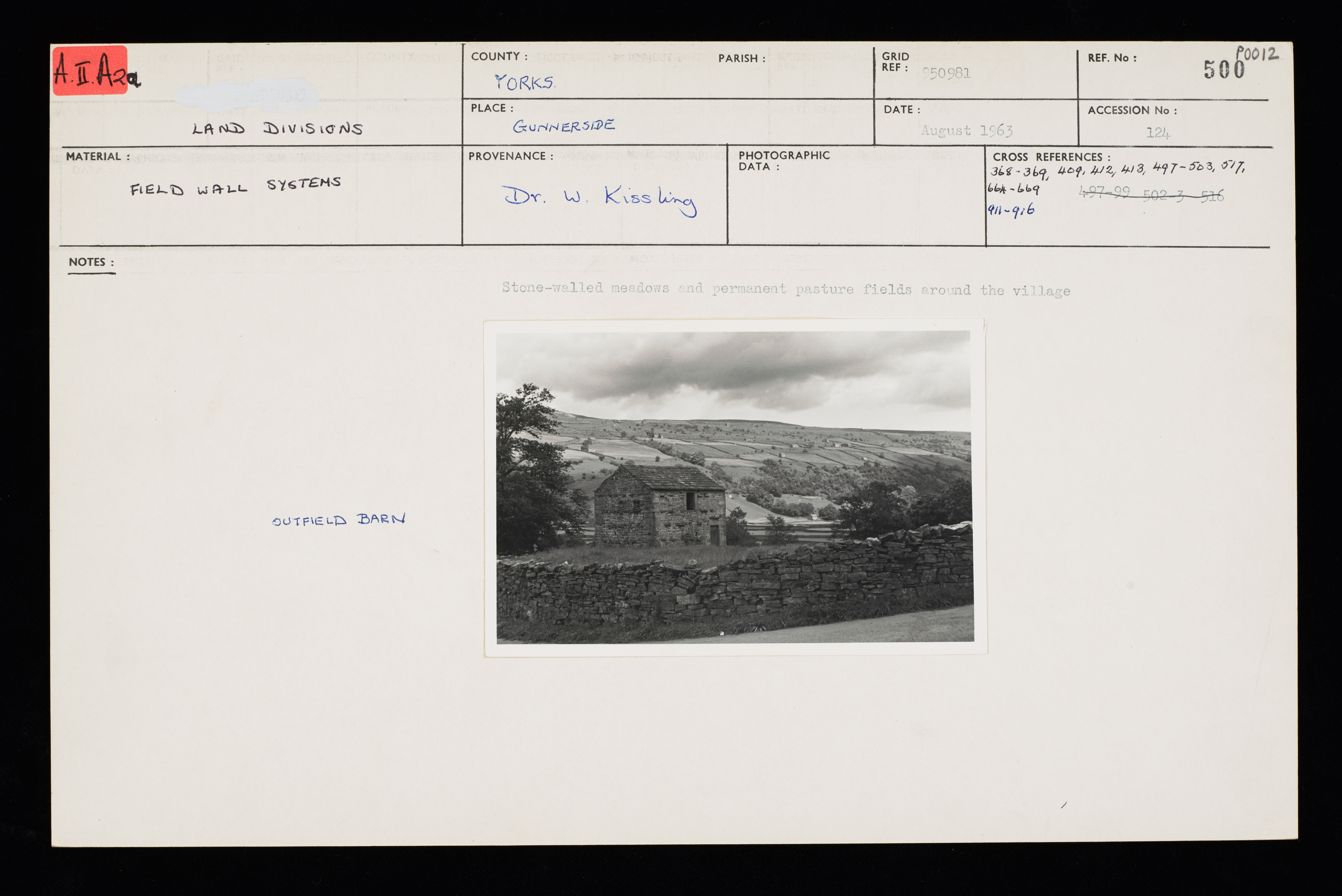 view on a dry stone wall in front of a barn framed by fields.
