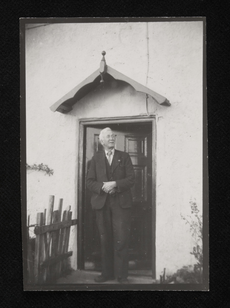 A man in a suit standing in front of his front door.