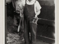 Male informant holding a smithy-made horse gag, in the doorway of stables at Finghall ( Wensleydale).