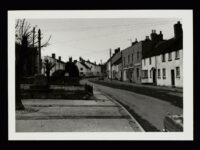 View looking down the main street in Stogursey (Somerset), showing dwelling houses, a post office and village shop.