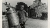 Fred Benson of Preston-under-Scar, ( Wensleydale) bringing empty milk churns to a farm near Redmire for milking time, using a handcart.