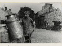 Fred Benson of Preston-under-Scar, ( Wensleydale) bringing empty milk churns to a farm near Redmire for milking time, using a handcart.